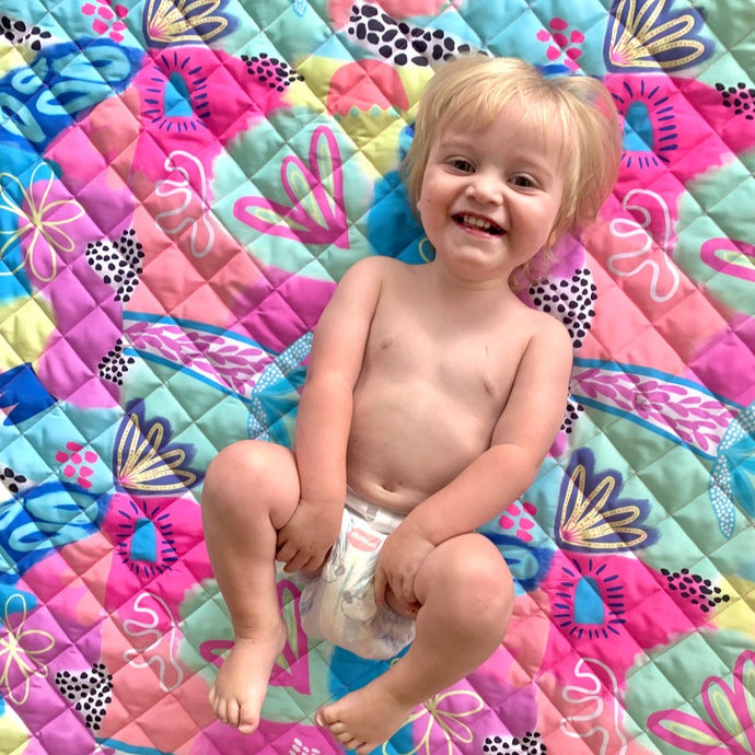toddler on pink green blue yellow colourful play mat